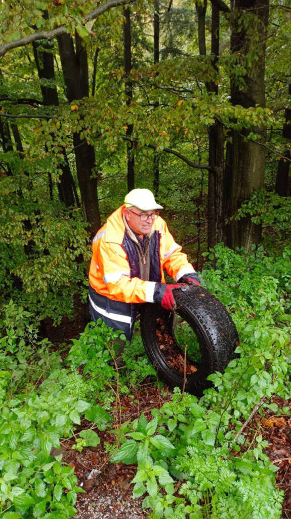 Dobrovolník vynáša z nelegálnej skládky starú pneumatiku